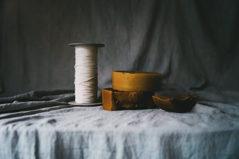 organic cotton spool on a table next to raw unfiltered organic beeswax with a cotton backdrop